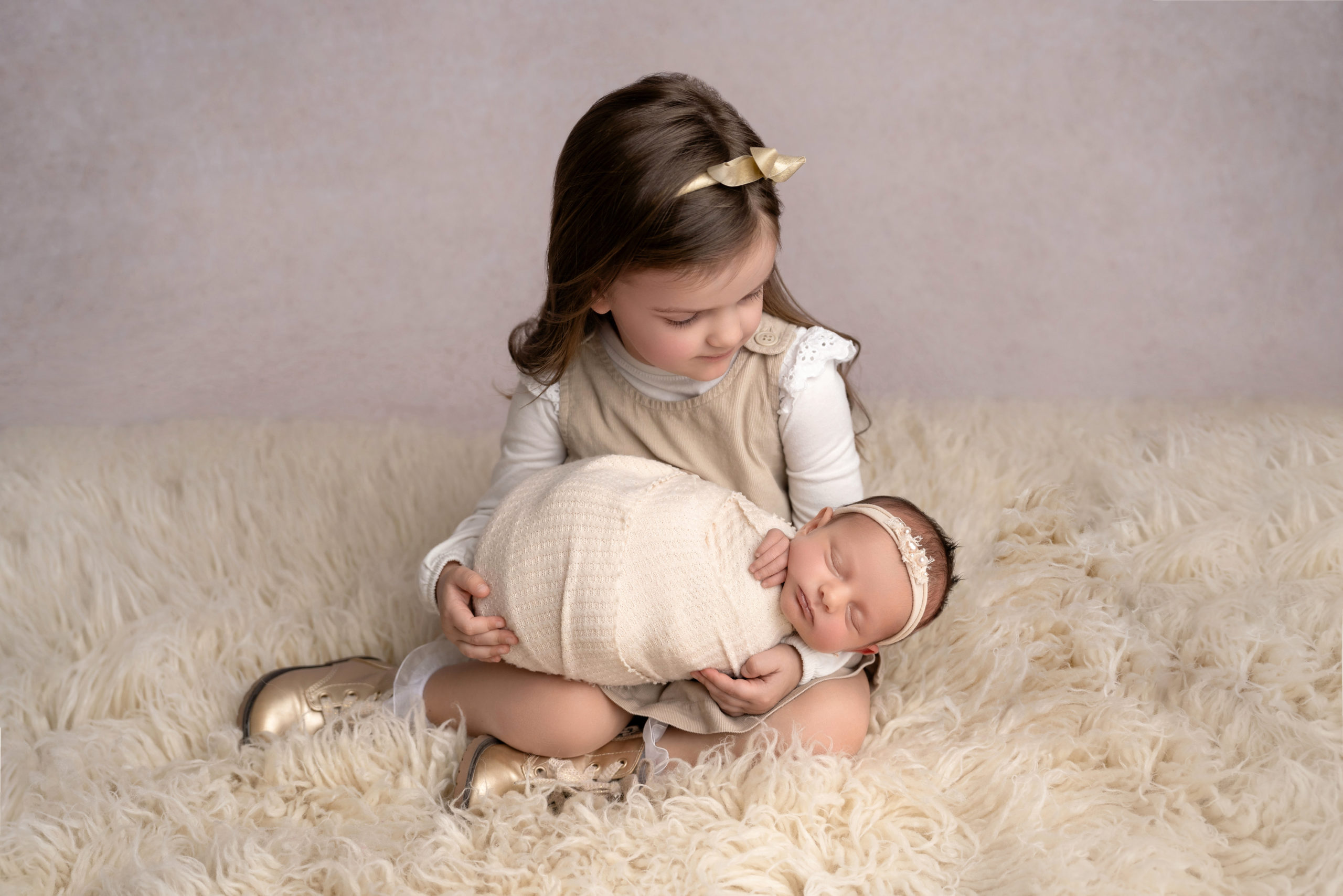 big sister holds newborn baby sister