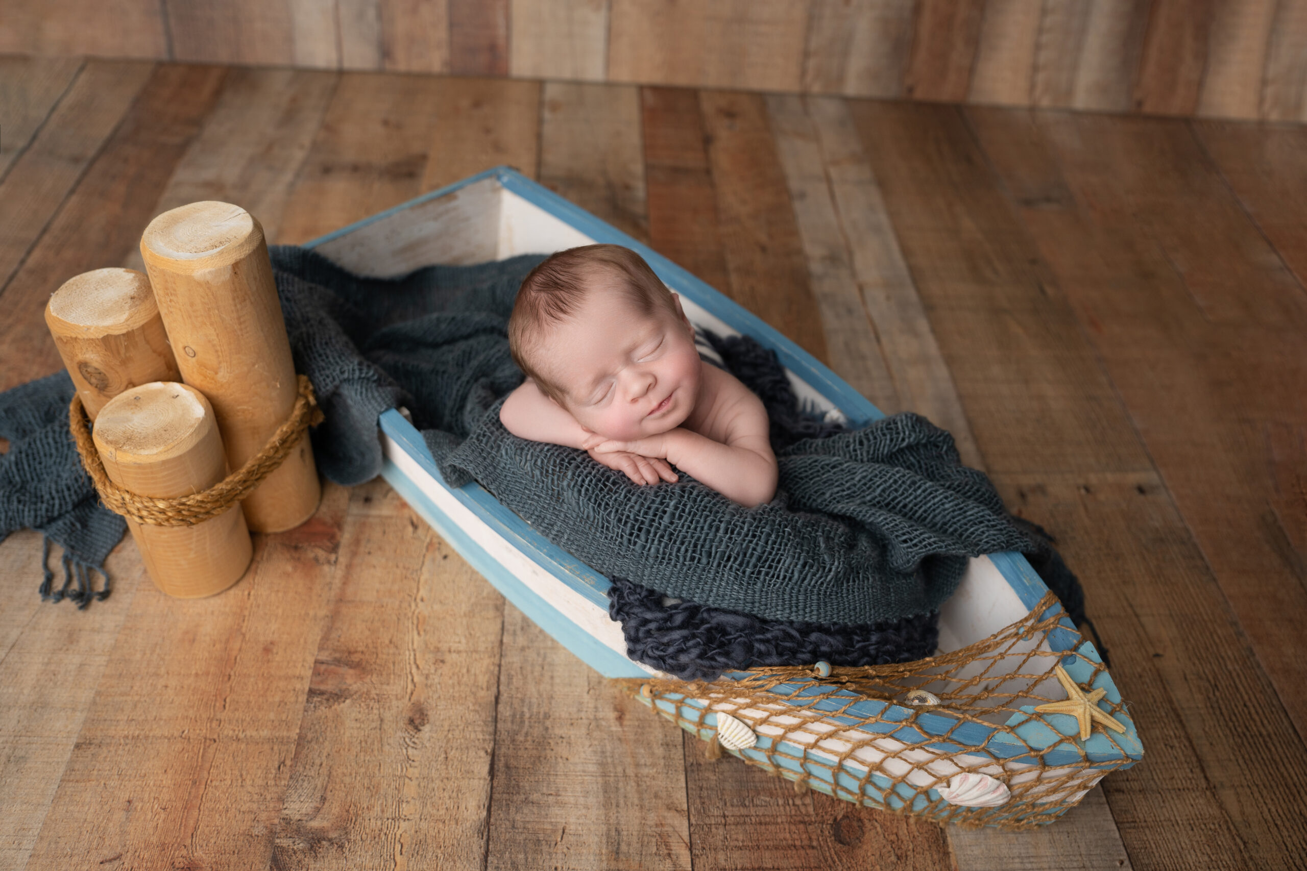 newborn boy posed in little canoe