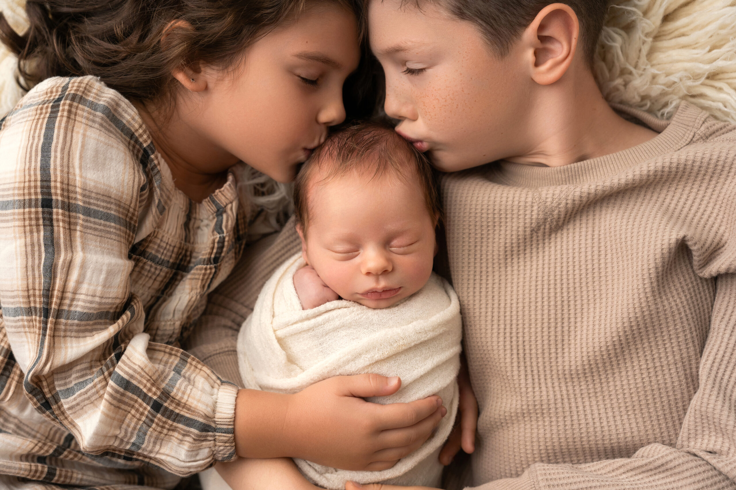 brother and sister kiss newborn baby sister